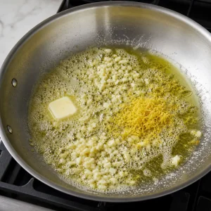 Knoblauch und Zitronenschale brutzeln in Butter und Olivenoel