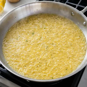 Orzo koechelt in Bruehe mit glaenzender Zitronen-Knoblauch-Sauce
