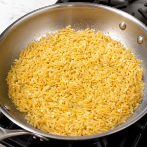 Orzo roestet in Zitronen-Knoblauch-Butter in einer Pfanne
