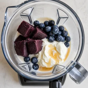 Acai, blueberries, Greek yogurt, almond milk, and honey added to a blender