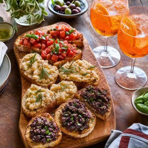 Prato italiano de aperitivo finalizado com coqueteis Aperol Spritz e tres variedades de bruschetta