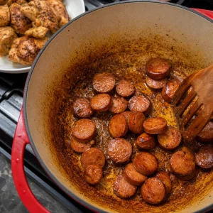 Andouille-Scheiben werden im gewürzten Topf gebräunt