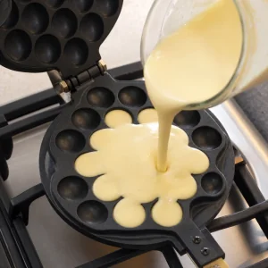 Bubble-Waffelteig wird in die Mitte des Wabeneisens gegossen.