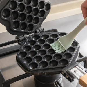 Bubble-Waffeleisen wird eingeölt und zum Backen vorgeheizt.