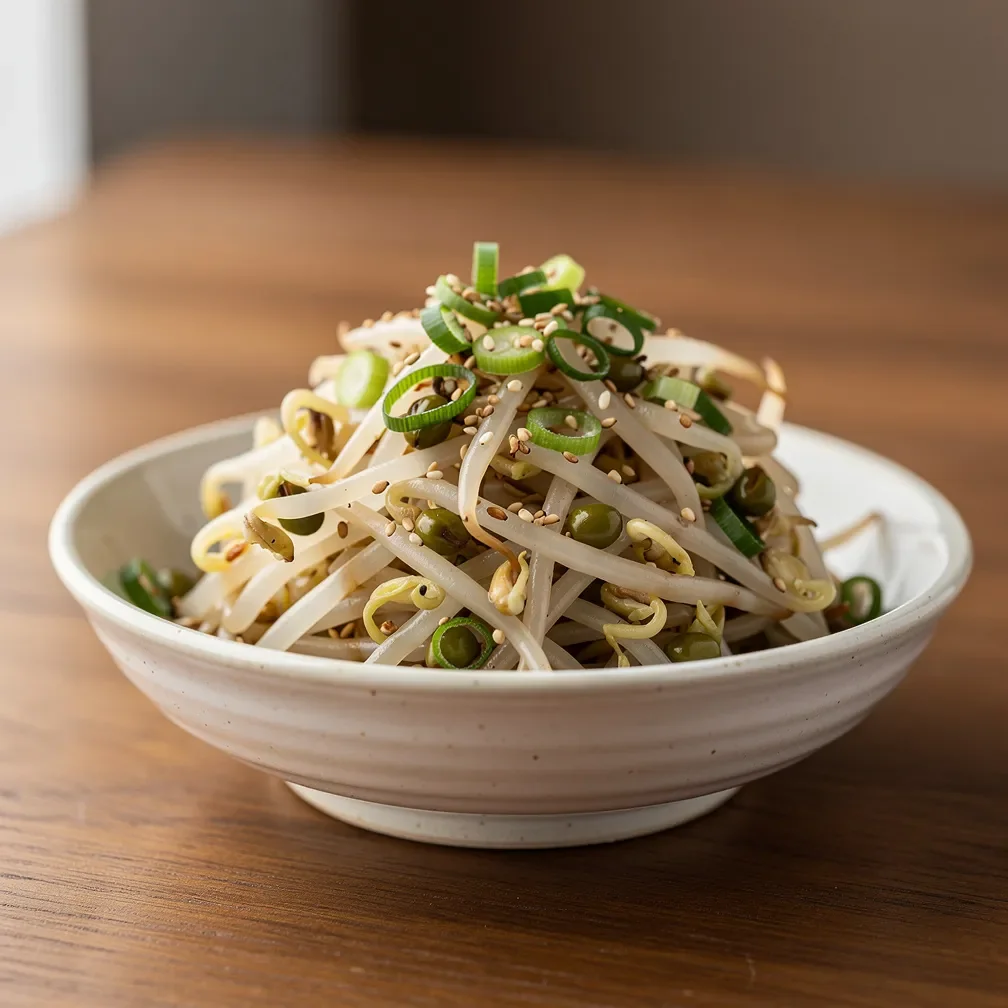 A small bowl of Korean seasoned mung bean sprouts garnished with sesame seeds and chopped green onions