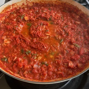 Tomato paste and white wine simmering into a thicker tomato sauce