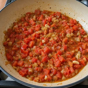Pomodori, aglio e origano cuociono in un sugo rustico