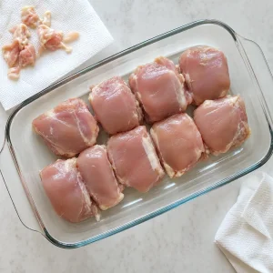 Raw chicken thighs arranged in a glass baking dish