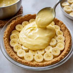 Crema tiepida versata sulle fette di banana nella base