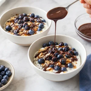 Warm melted chocolate drizzled in thin streams over blueberry yogurt bowls
