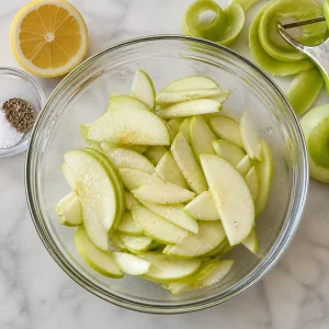Thin Granny Smith apple wedges tossed with lemon juice, salt, and pepper for Brie-and-Apple Tarte Tatin Bites