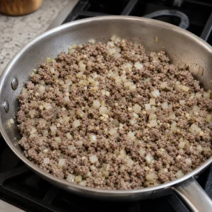 Ground pork and beef cooking with onion and garlic in a skillet