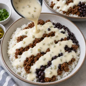 Warm white queso sauce drizzled over beef rice and black beans