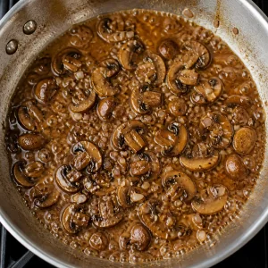 Marsala wine simmering with mushrooms in the skillet
