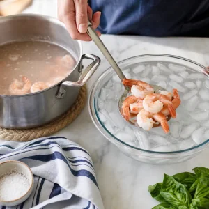 Cooked shrimp being transferred into an ice bath for chilled skewers