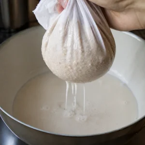 Latte di nocciole che filtra attraverso un telo in una ciotola