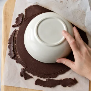 Firm chocolate wafer dough trimmed into a round with a bowl