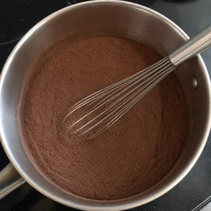 Mélange sec au cacao dans une casserole avec un fouet