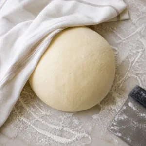 Smooth pretzel dough resting on a floured surface