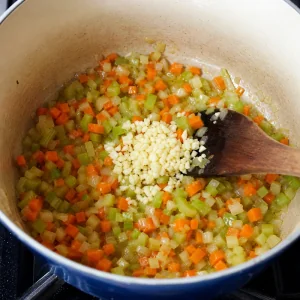 Alho picado adicionado a cebola, aipo e cenouras amolecidos para minestrone