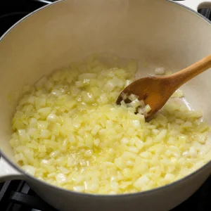 Cebolas refogando em azeite numa panela grande para sopa de legumes