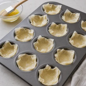 Phyllo squares pressed into mini muffin tin cups and brushed with butter.