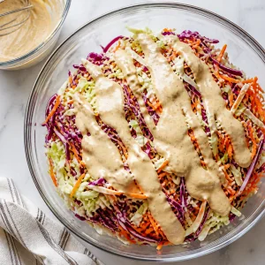 Creamy dressing poured over shredded cabbage and carrots