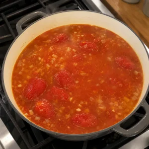 Canned tomatoes and vegetable broth simmering in a soup pot