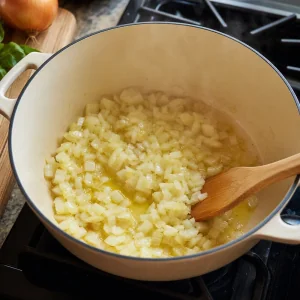 Diced onion softening in olive oil for creamy tomato Parmesan soup