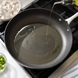 Óleo vegetal brilhando em uma frigideira antiaderente grande pronta para o tofu.