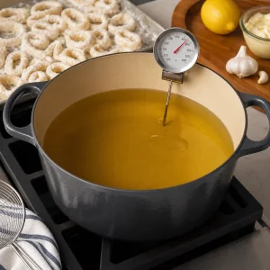 Vegetable oil heating in a heavy pot with a thermometer for frying calamari.