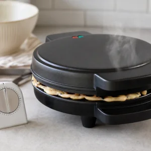 Piastra per waffle chiusa con vapore mentre cuoce un waffle al mochi.