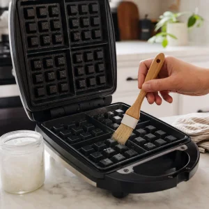 Piastra per waffle aperta unta leggermente con olio di cocco.