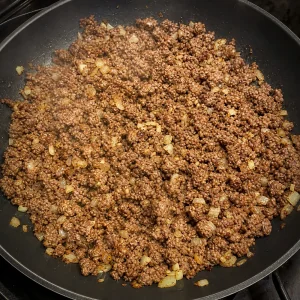 Ground beef browned and broken apart with onions in a skillet