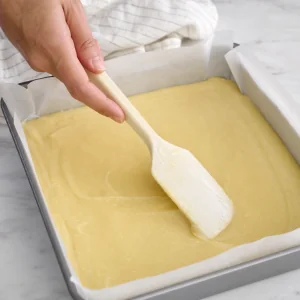 Massa de mochi de manteiga alisada uniformemente na forma forrada