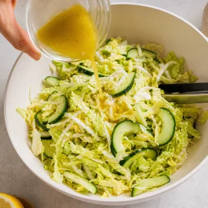 Molho de limao e azeite vertido sobre salada de couve napa e pepino