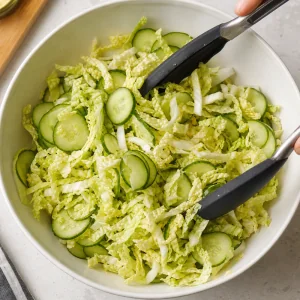Couve napa fatiada e pepino em rodelas misturados numa saladeira
