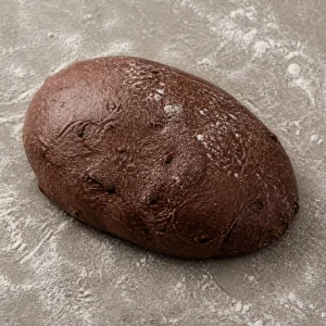밀가루를 뿌린 표면 위의 매끈하고 탄력 있는 다크 초콜릿 빵 반죽