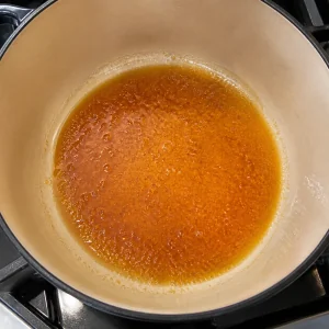 Amber sugar and oil bubbling in the bottom of a heavy pot
