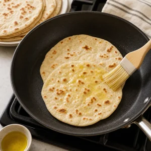 Flatbread warming in a skillet with olive oil for chicken shawarma wraps
