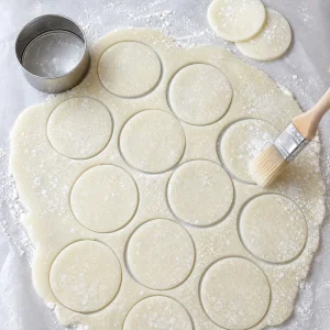 Round mochi dough circles cut from the chilled sheet and dusted clean.