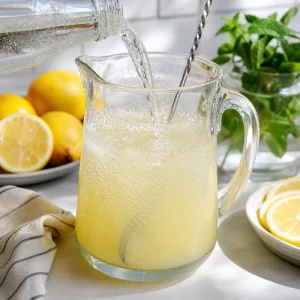 Sprudelwasser wird in einen Krug mit Zitronenbasis gegossen