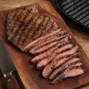 Grilled flat iron steak resting on a cutting board and sliced thinly against the grain