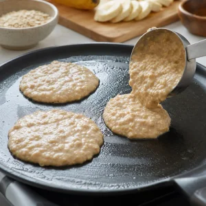 Oat pancake batter poured onto a lightly buttered skillet