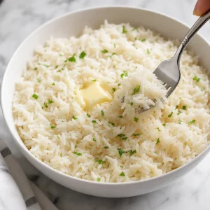 Fluffiger weisser Reis wird mit einer Gabel und Butter aufgelockert