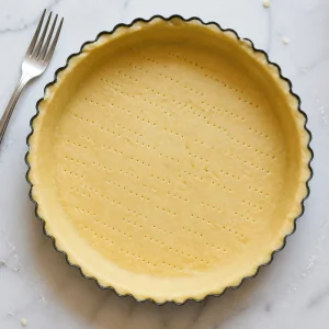 Raw tart shell with small fork holes across the base