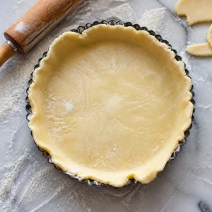Rolled pastry dough fitted into a fluted tart pan