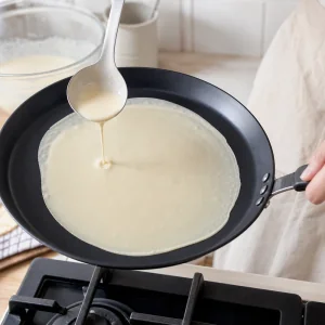 Crepe batter poured and swirled thinly across the pan
