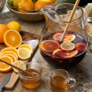 Rodelas de laranja e limao adicionadas a um jarro com vinho tinto, conhaque e mel para sangria.