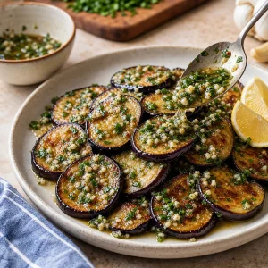 Garlic parsley dressing spooned over plated fried eggplant